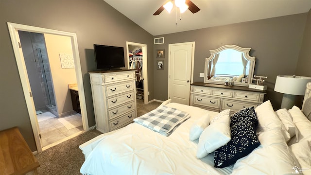 carpeted bedroom with visible vents, ensuite bath, a walk in closet, vaulted ceiling, and a closet