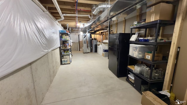 unfinished basement with water heater and freestanding refrigerator