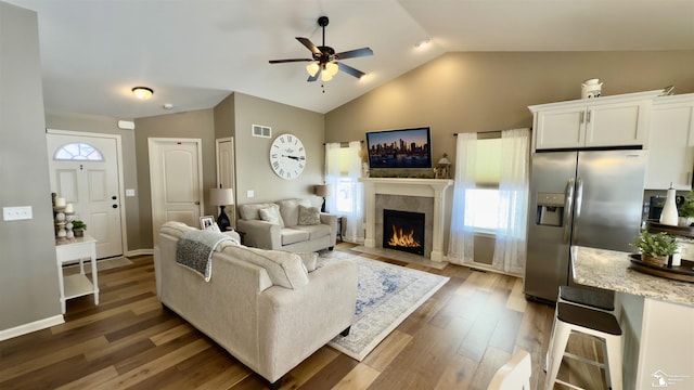 living room with dark wood-type flooring, a wealth of natural light, visible vents, and vaulted ceiling