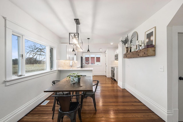 dining room with dark wood-type flooring, visible vents, and baseboards