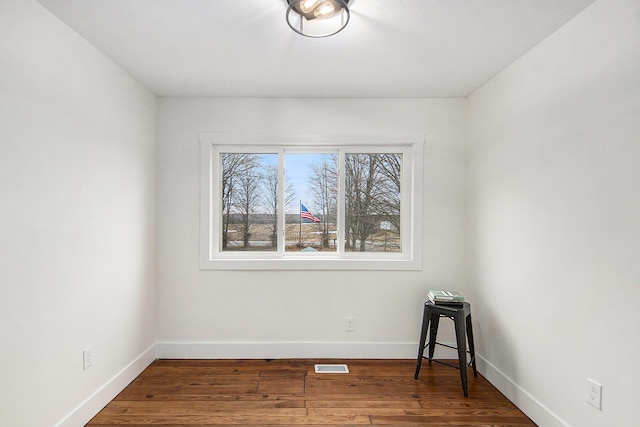 unfurnished room featuring wood finished floors, visible vents, and baseboards