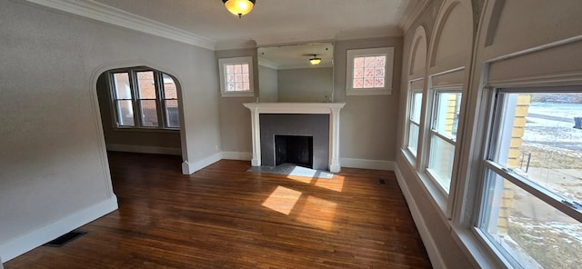 unfurnished living room featuring visible vents, a fireplace with flush hearth, wood finished floors, crown molding, and a healthy amount of sunlight