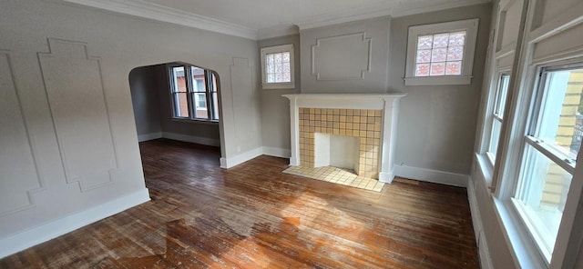 unfurnished living room with arched walkways, crown molding, a fireplace, wood finished floors, and baseboards