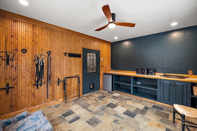 bar with refrigerator, recessed lighting, a ceiling fan, stone finish floor, and wood walls