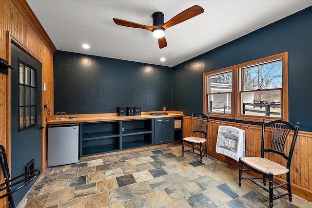 sitting room featuring a ceiling fan, heating unit, and stone finish floor