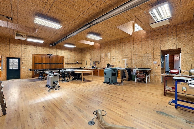 misc room featuring a towering ceiling, wood-type flooring, visible vents, and a workshop area