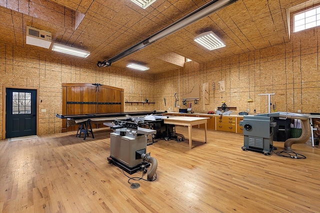 misc room with a towering ceiling, light wood finished floors, and a workshop area