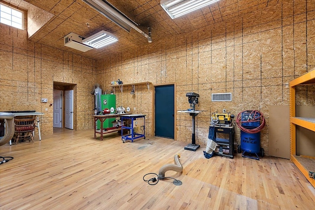 misc room with a towering ceiling, visible vents, and hardwood / wood-style floors