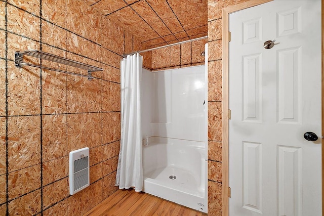 bathroom with a shower with shower curtain, wood finished floors, and heating unit