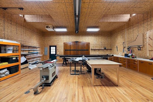 miscellaneous room featuring a high ceiling, electric panel, and light wood-style flooring