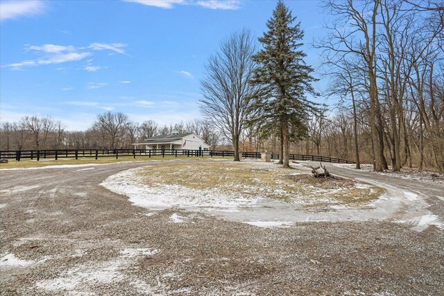 view of yard featuring fence and dirt driveway