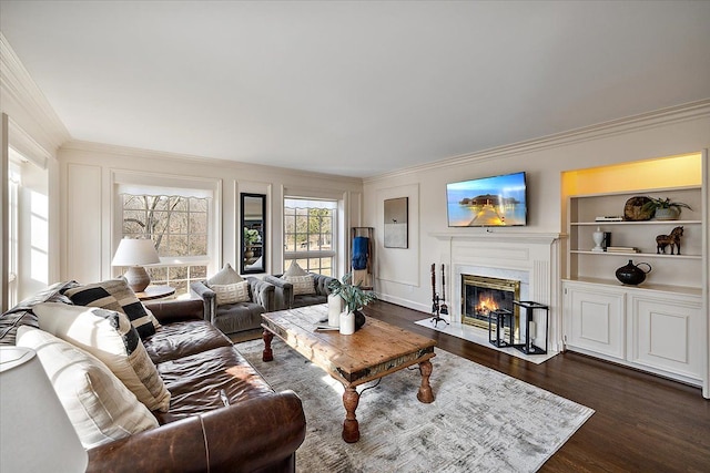 living room with crown molding, a fireplace with flush hearth, dark wood-type flooring, and built in shelves