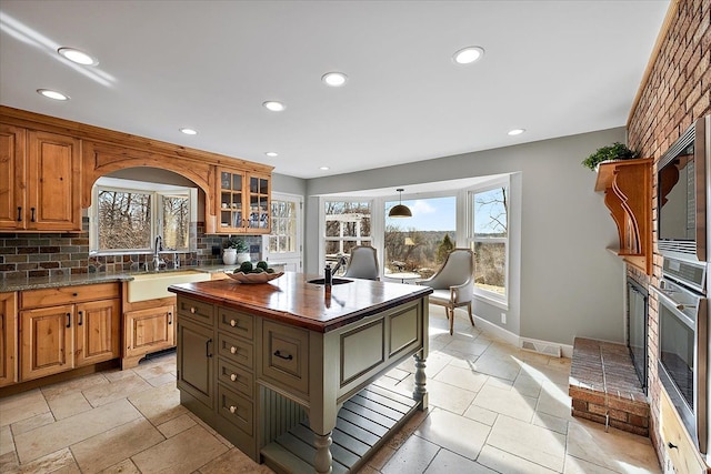 kitchen with oven, a sink, recessed lighting, tasteful backsplash, and glass insert cabinets