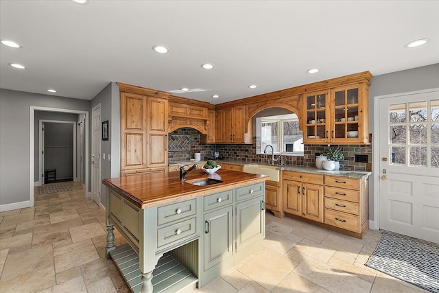 kitchen featuring backsplash, recessed lighting, baseboards, and a sink