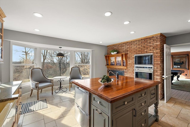 kitchen with a brick fireplace, wood counters, appliances with stainless steel finishes, and plenty of natural light