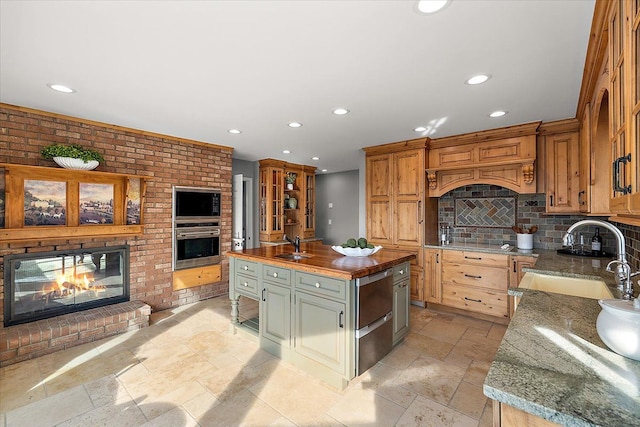 kitchen with stainless steel appliances, recessed lighting, a sink, and a fireplace
