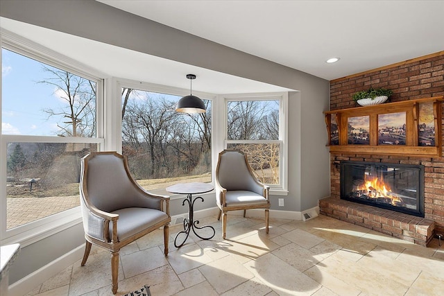 sitting room with baseboards, a brick fireplace, recessed lighting, and stone tile flooring