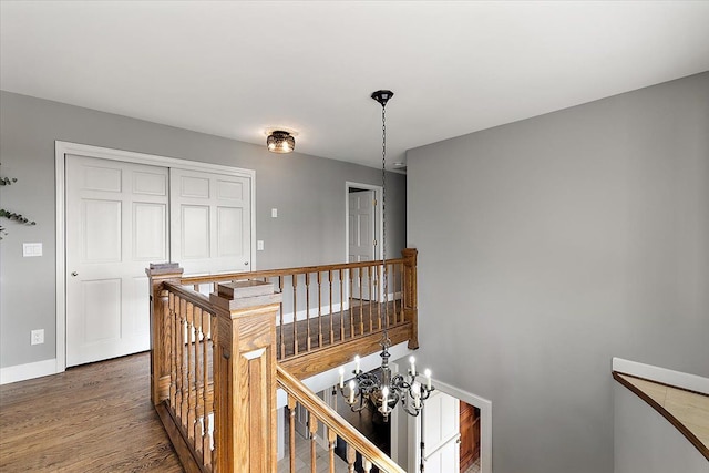 corridor featuring baseboards, dark wood-style floors, and an upstairs landing