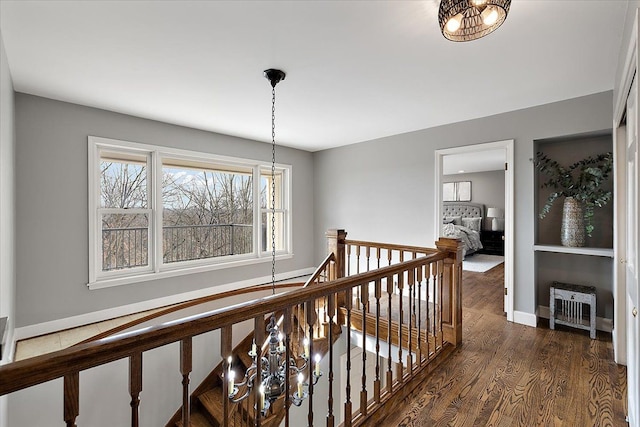 hall with baseboards, dark wood-style floors, and an upstairs landing