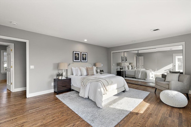 bedroom with recessed lighting, baseboards, wood finished floors, and a closet
