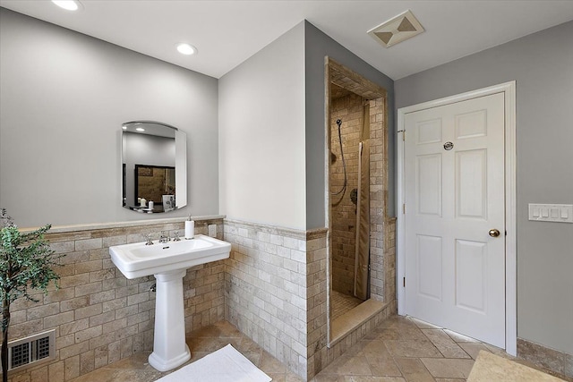 bathroom with visible vents, a wainscoted wall, and a stall shower