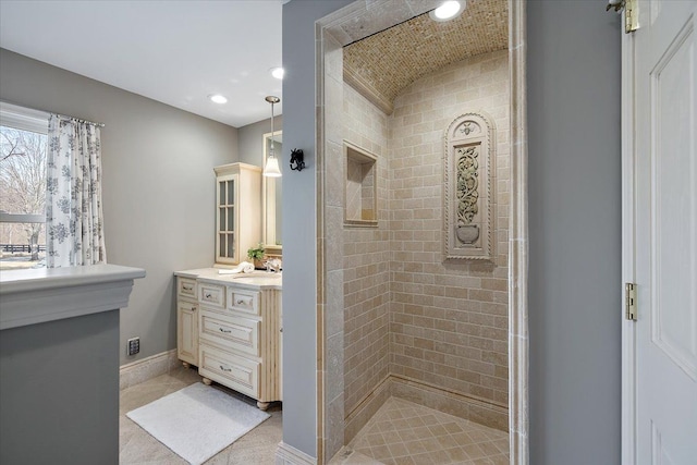bathroom with vanity, lofted ceiling, baseboards, recessed lighting, and a tile shower