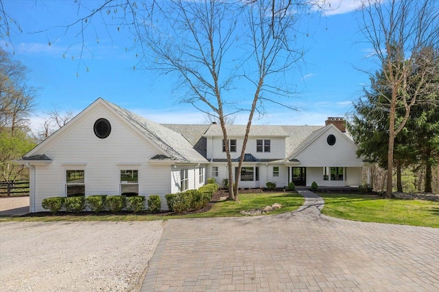 view of front facade with fence, a chimney, a porch, and a front lawn