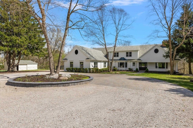 view of front of home featuring curved driveway, an outdoor structure, and a front lawn