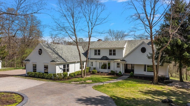 view of front of property featuring a porch, decorative driveway, and a front lawn