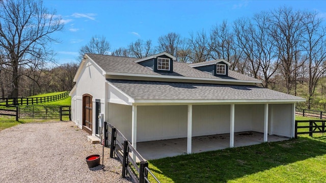 view of side of home with roof with shingles, fence, and a yard