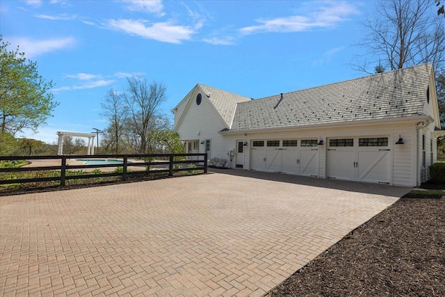 view of side of property with decorative driveway, fence, and a garage