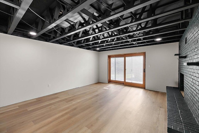 unfurnished living room featuring light wood finished floors and a brick fireplace