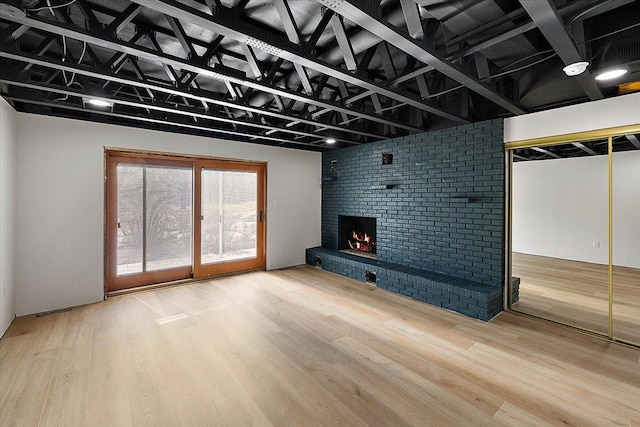 unfurnished living room with a brick fireplace and wood finished floors