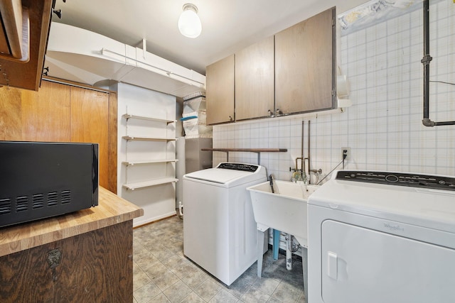 washroom featuring cabinet space, tile walls, and washer and dryer