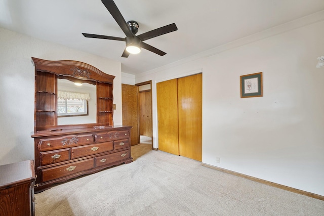 unfurnished bedroom with baseboards, ceiling fan, a closet, and light colored carpet