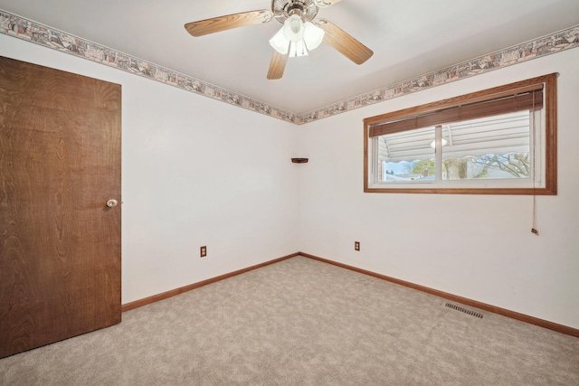 carpeted empty room with ceiling fan, visible vents, and baseboards