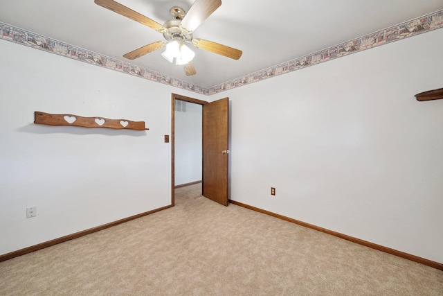 carpeted spare room with a ceiling fan, visible vents, and baseboards