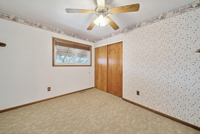 unfurnished bedroom with carpet, a closet, ceiling fan, baseboards, and wallpapered walls