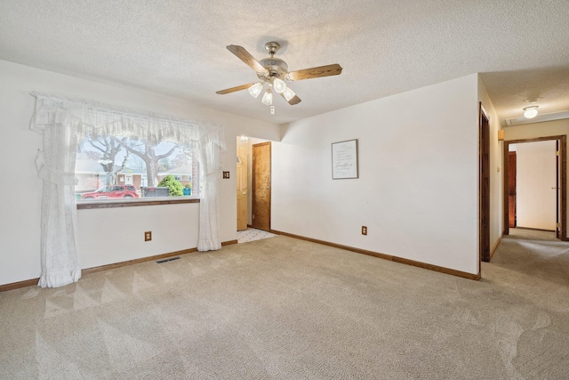 carpeted empty room featuring a textured ceiling, ceiling fan, visible vents, and baseboards