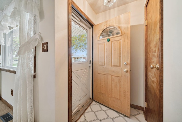 foyer with baseboards, visible vents, and light floors