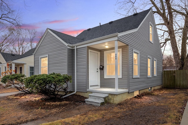 view of front of house featuring roof with shingles and fence