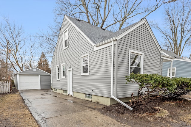 view of side of home with a garage, an outbuilding, concrete driveway, and roof with shingles