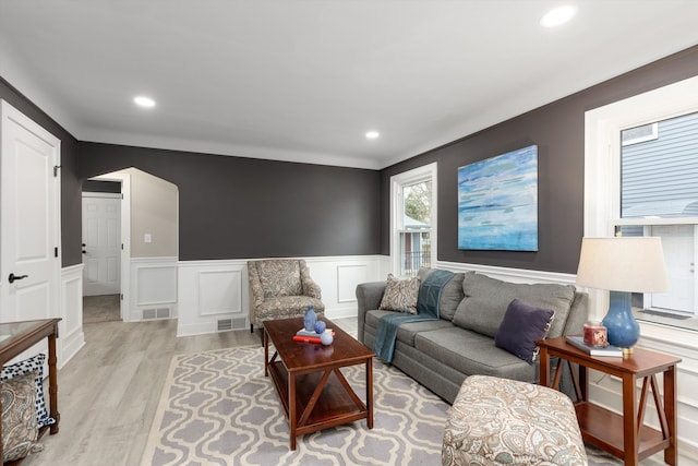 living room featuring arched walkways, visible vents, light wood finished floors, and recessed lighting