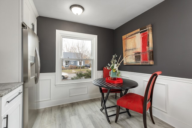 dining area with wainscoting and light wood finished floors