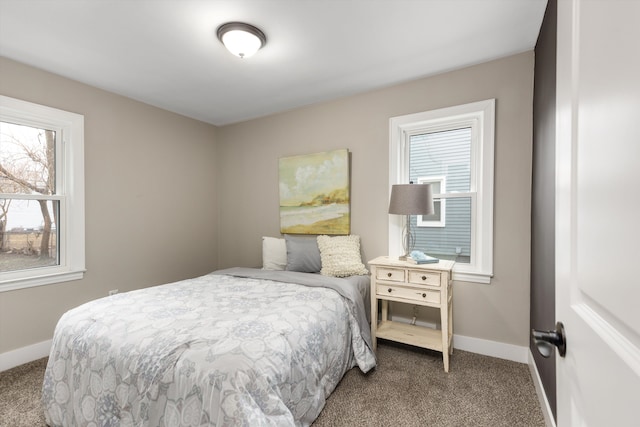 carpeted bedroom featuring multiple windows and baseboards