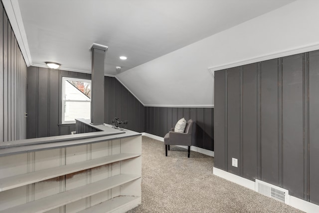 carpeted bedroom with lofted ceiling, visible vents, wood walls, and baseboards