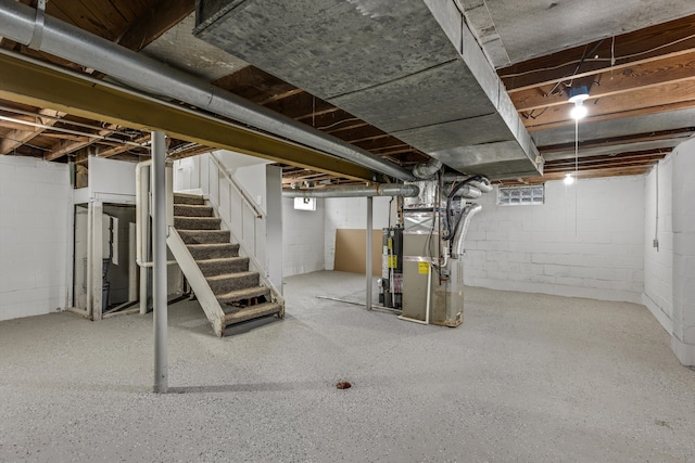 unfinished below grade area featuring heating unit, stairs, and gas water heater