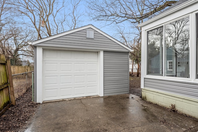 detached garage featuring aphalt driveway and fence