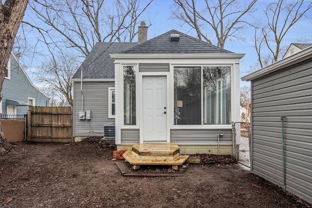 rear view of property with central AC, fence, roof with shingles, a gate, and a chimney