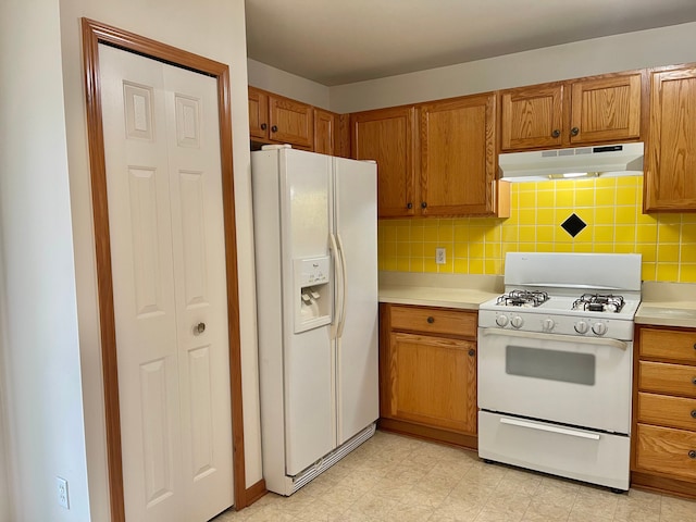 kitchen with white appliances, tasteful backsplash, under cabinet range hood, and light countertops